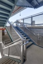 The rectangular openings in the FPZ-10 pattern allow natural light transmission, and the stainless steel metal fabric picks up the stairwells’ blue and green hues.